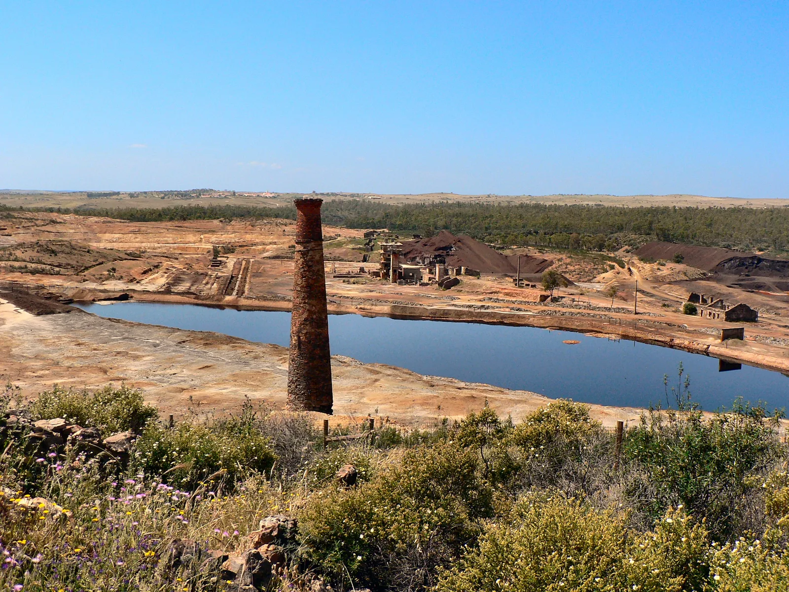 A corta inundada de água ácida vermelha das Minas de São Domingos, no Alentejo, com ruínas industriais em redor