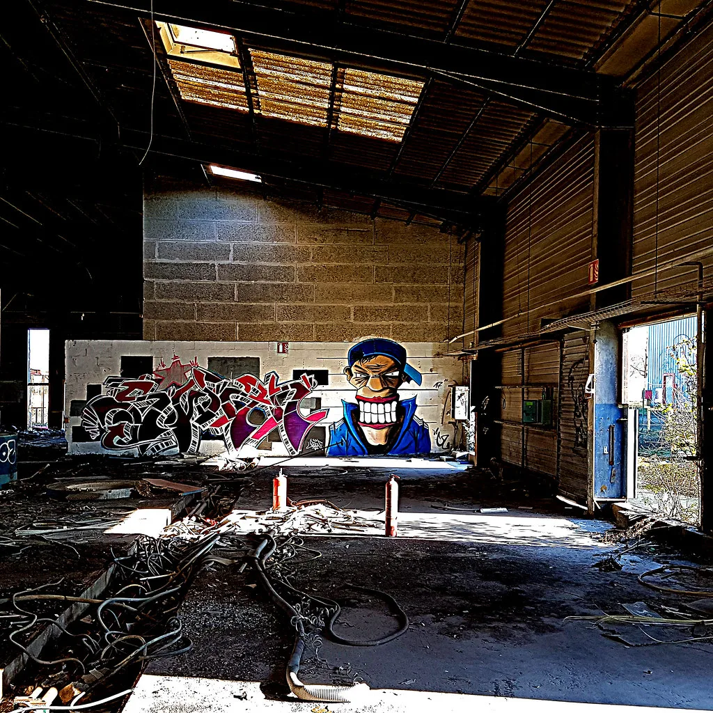 Intérieur de l'ancienne fonderie de l'Authion abandonnée aux Ponts-de-Cé : toiture rouillée, graffitis et gravats