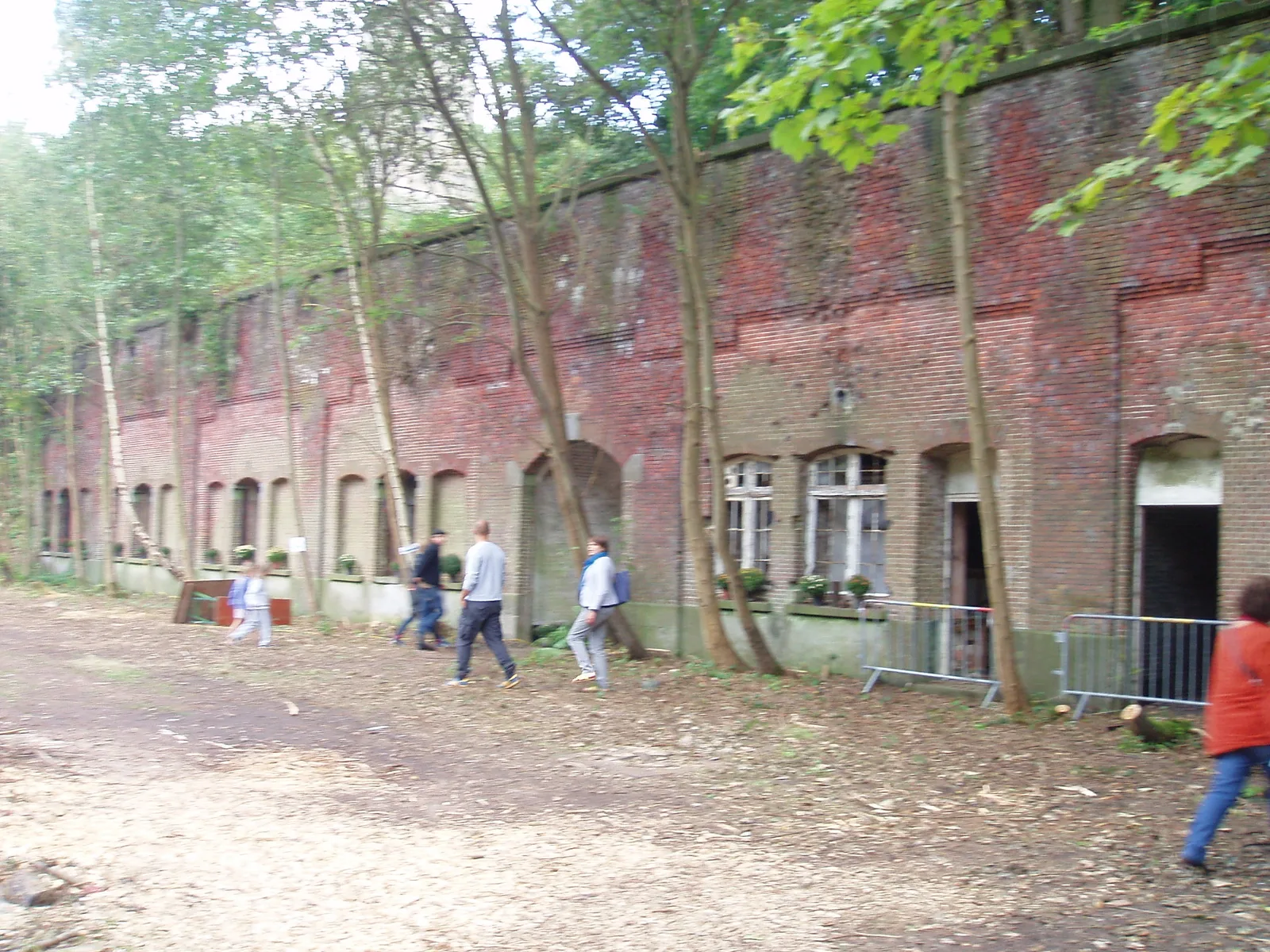 Façade de brique aux casemates en arc du Fort van Walem en ruine, envahie par les arbres