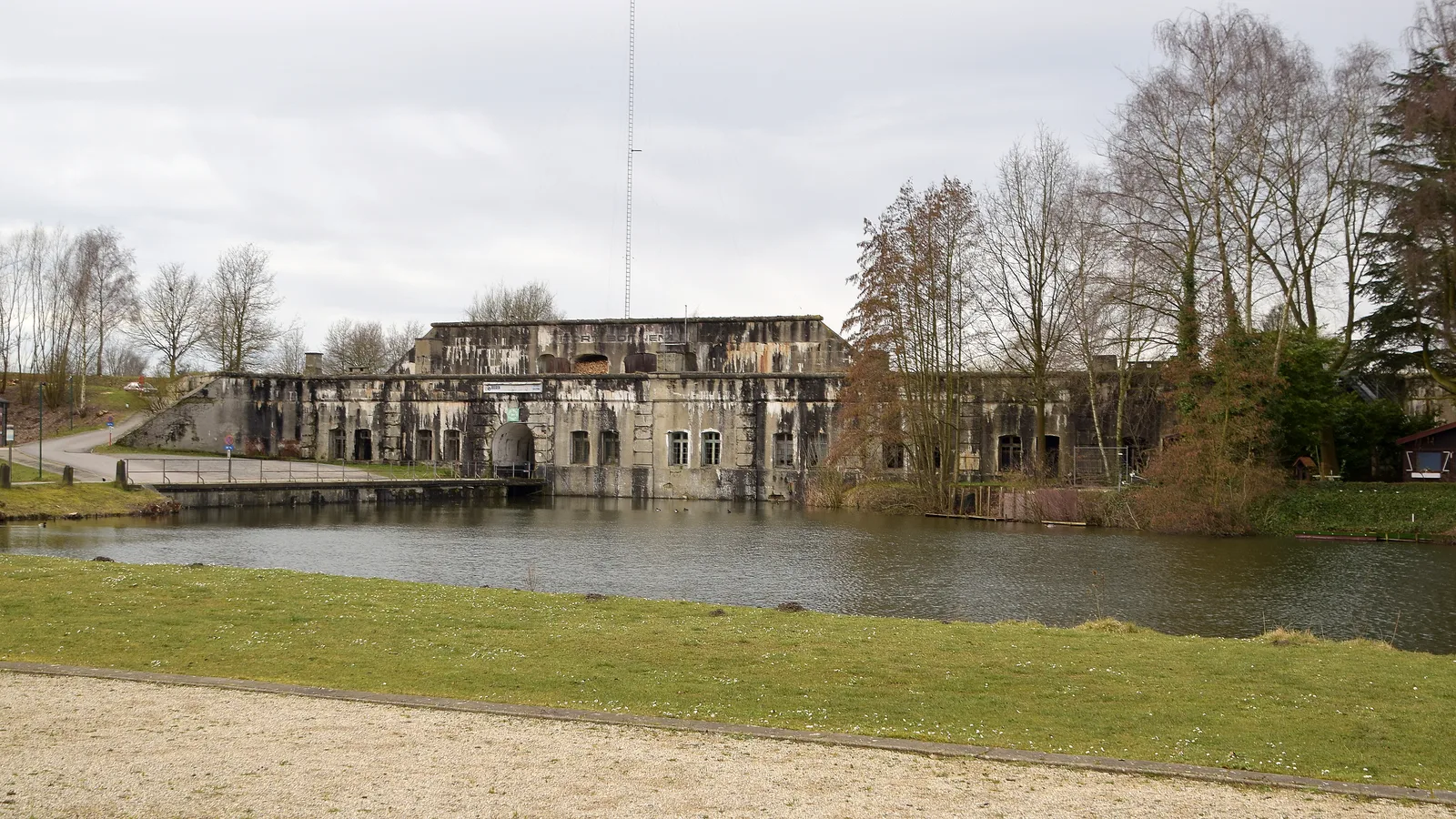 Le Fort van Bornem, bâtiment de béton envahi par la végétation et reflété dans ses douves