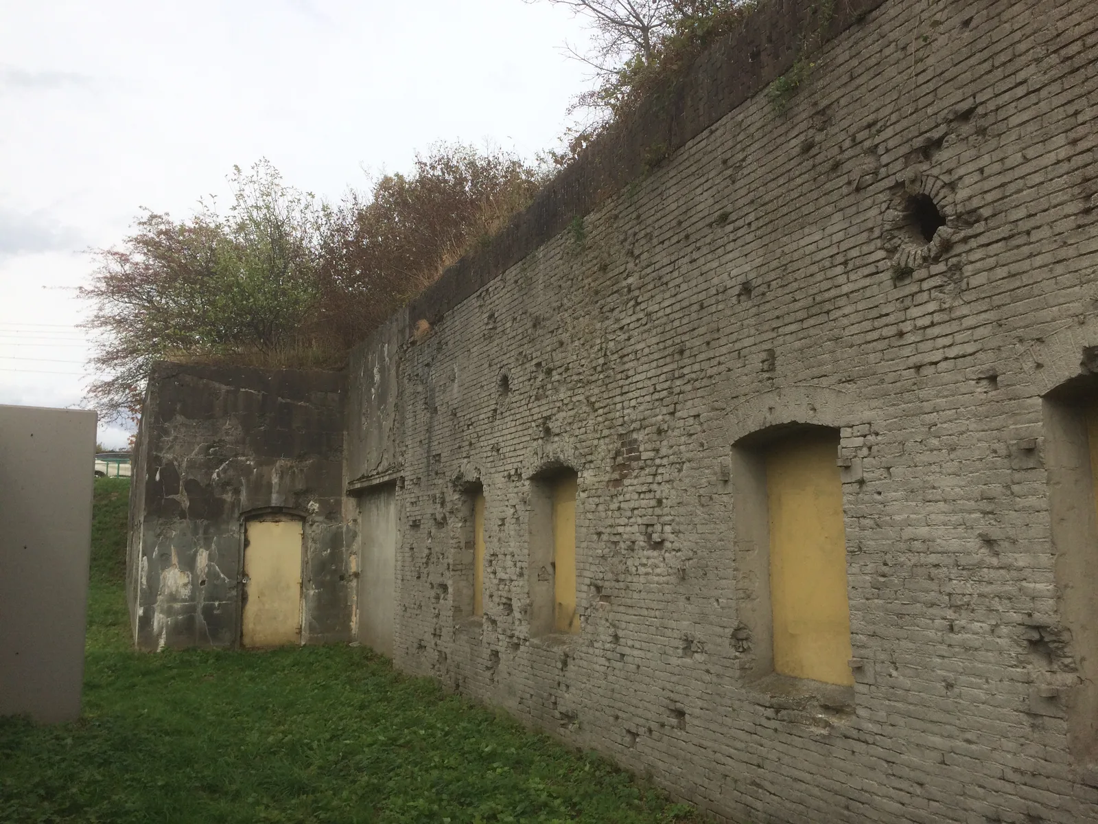 Overwoekerde, met kogelgaten doorzeefde bakstenen muur van het verlaten Fort Westervoort bij Arnhem