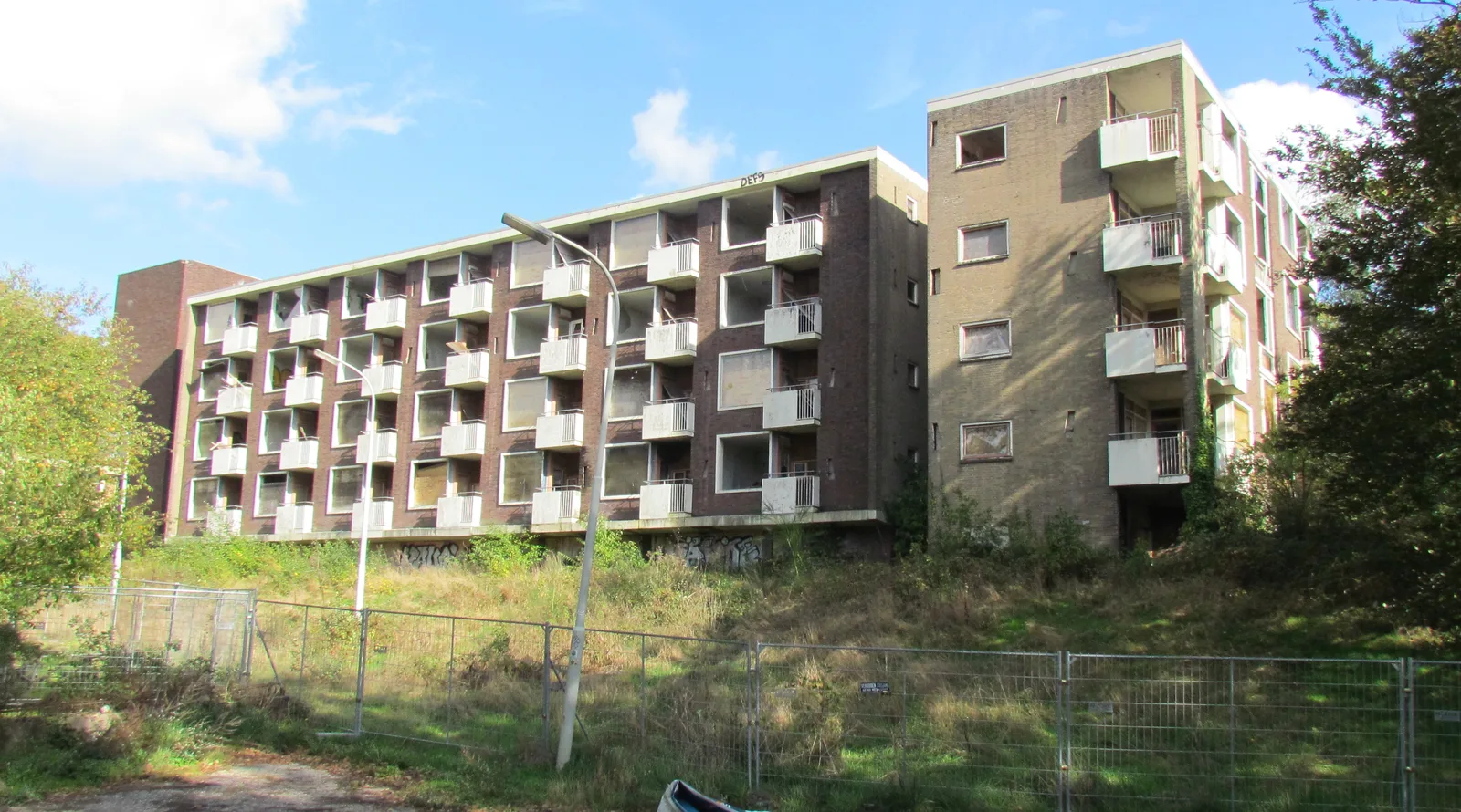 Vervallen, met hekken afgezette zorgflat van het voormalige Rhederhof in Rheden, balkons en lege ramen