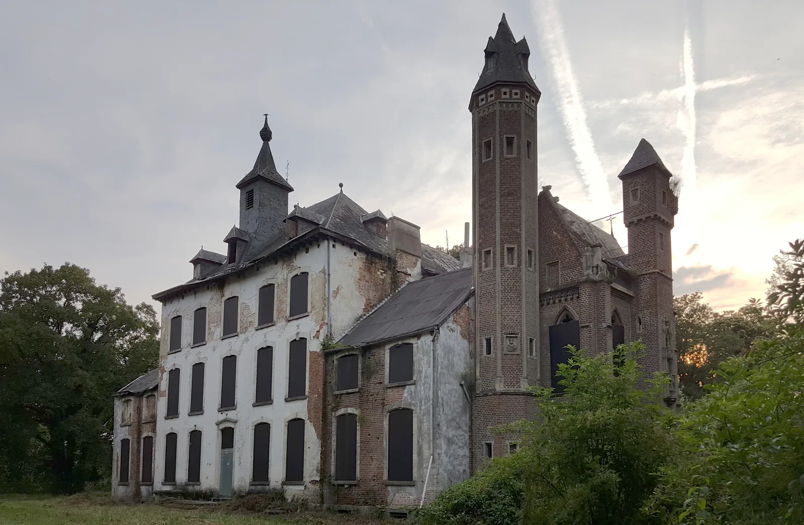 Le château abandonné Kasteel Hogemeyer à Kortenaken, tour néogothique et façade délabrée au coucher du soleil