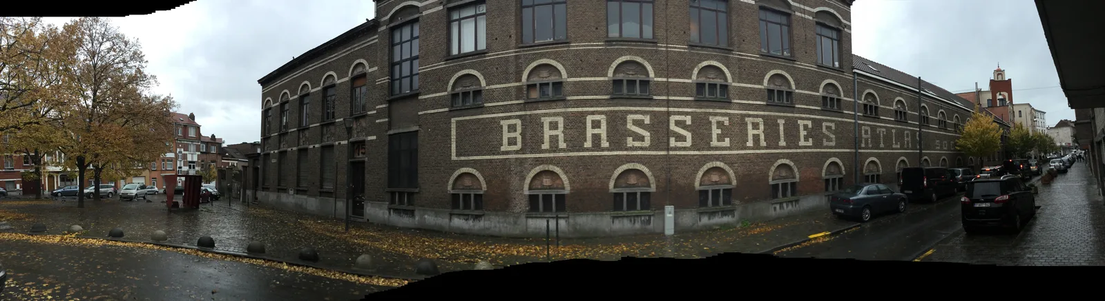 Brick facade of the former Atlas brewery in Anderlecht, with the inscription BRASSERIES ATLAS, on a rainy day