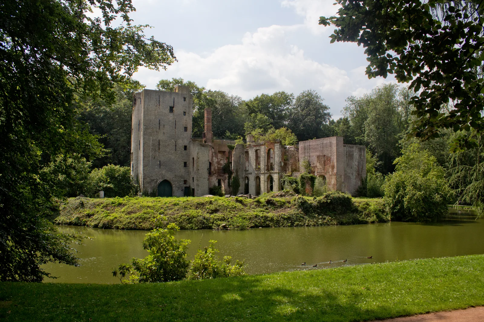 The ruin of the Prinsenkasteel of Grimbergen, roofless stone walls reflected in the moat of the Prinsenbos park