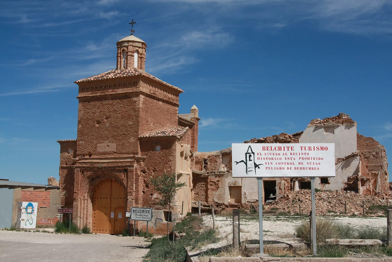 Ruinas del pueblo viejo de Belchite, con la iglesia de ladrillo y un cartel de Belchite Turismo