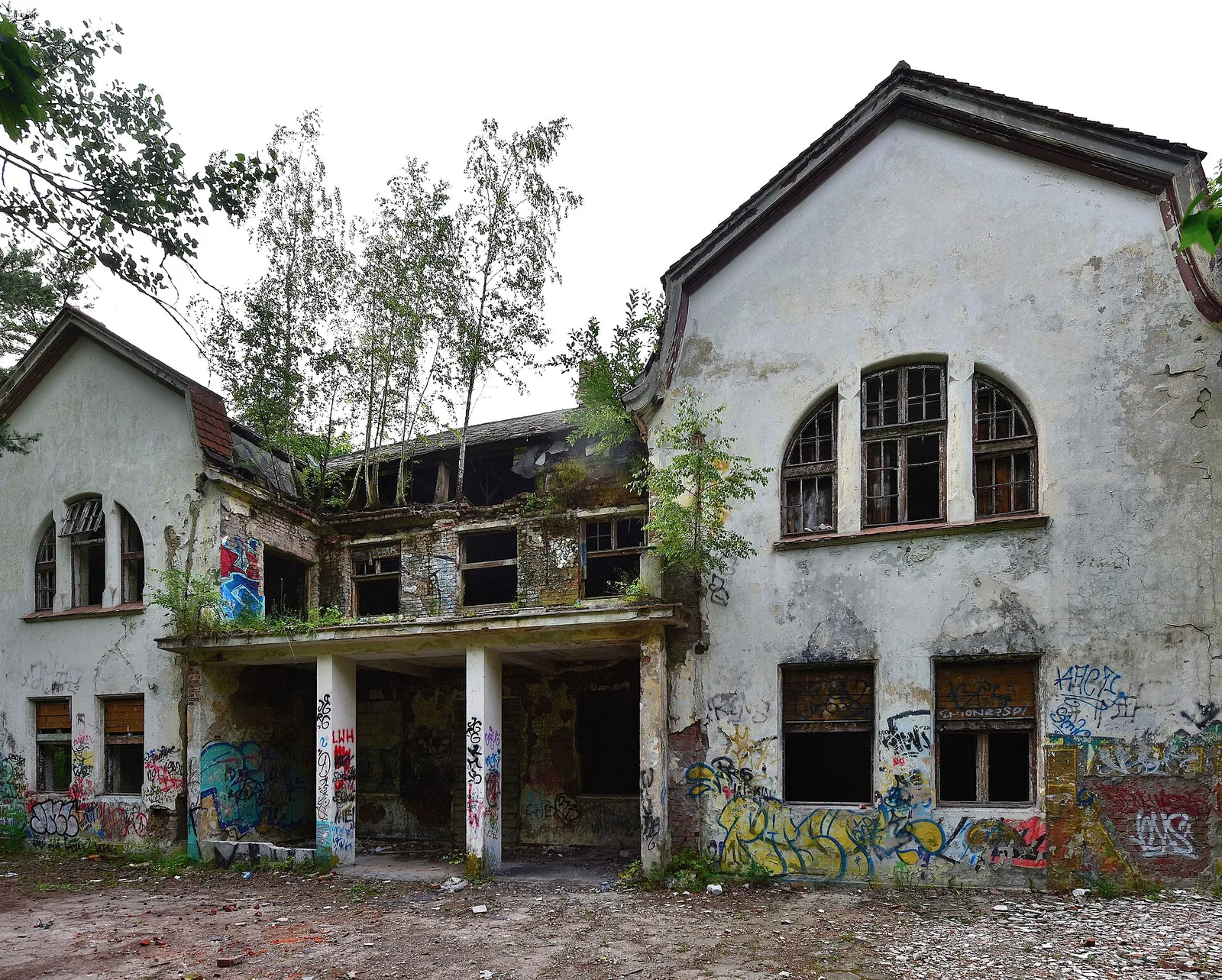 Opuszczony budynek sanatorium Zofiowka w Otwocku, popekane sciany, wybite okna i drzewa rosnace przez dach