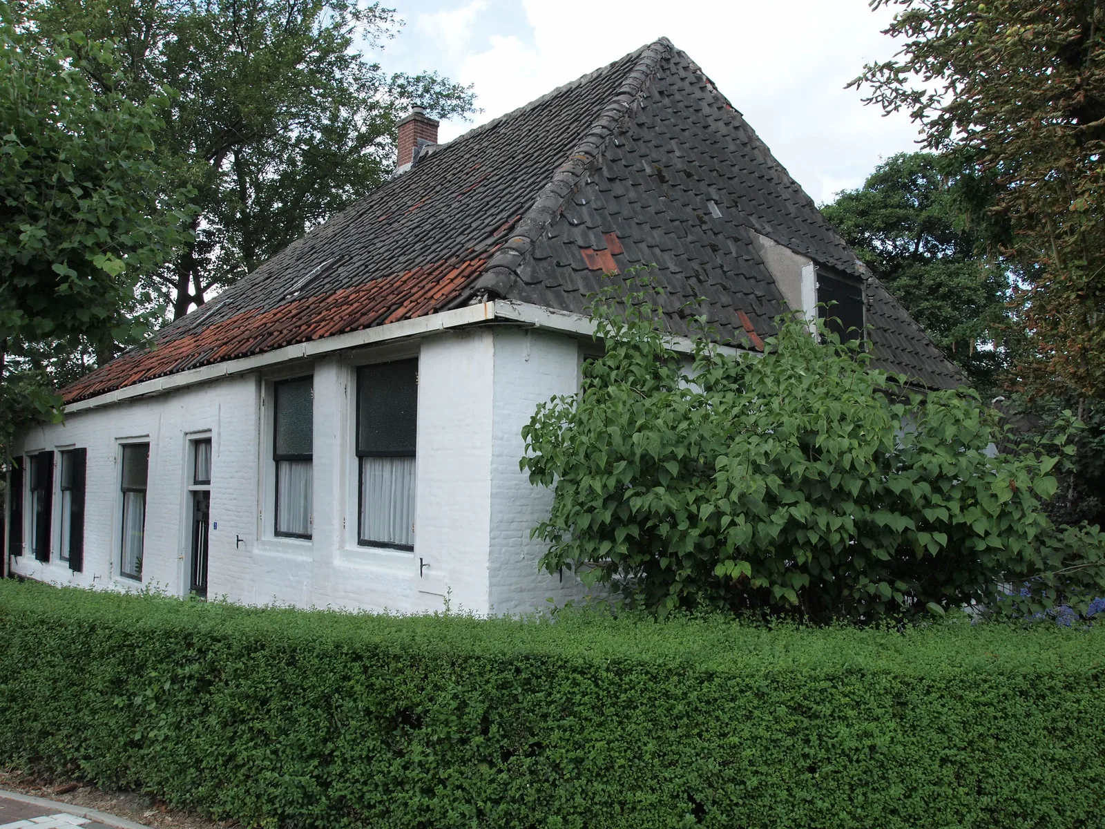 De vervallen, witgeschilderde monumentboerderij De Klop aan de Klopdijk in Utrecht-Overvecht, met mossig dak